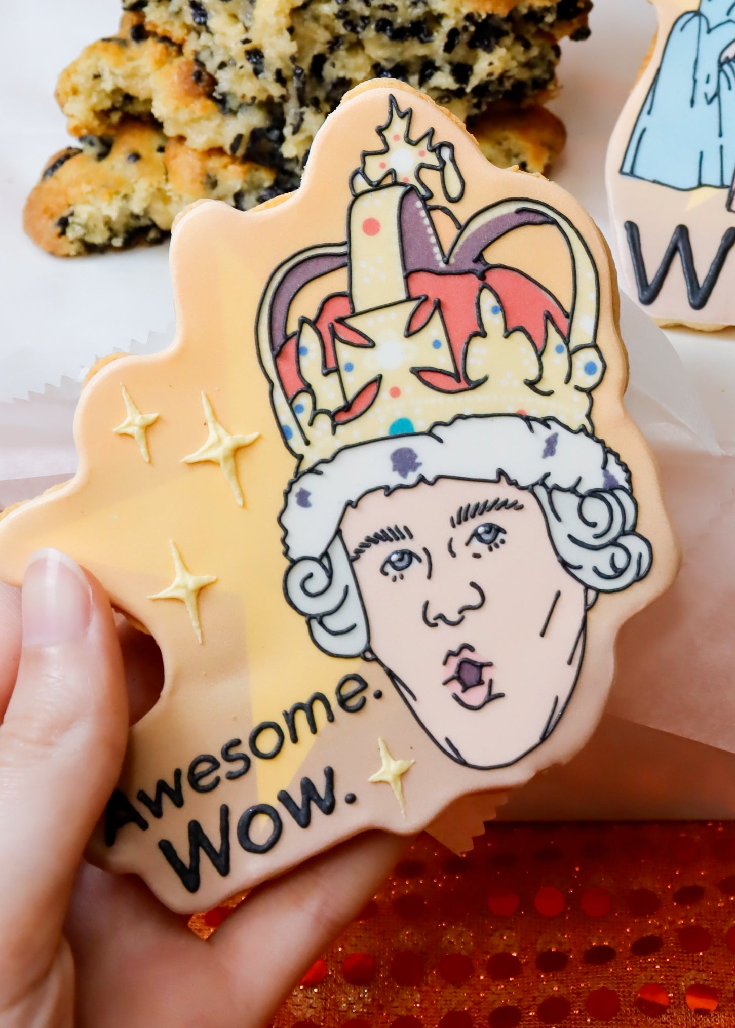 Decorated cookies featuring cartoon-style designs, one showing a crown with the word "awesome. Wow." and the other with figures and "WORK!" text