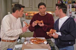 Chandler, Ross, and Joey from Friends stand around a kitchen counter eating pizza and engaging in conversation