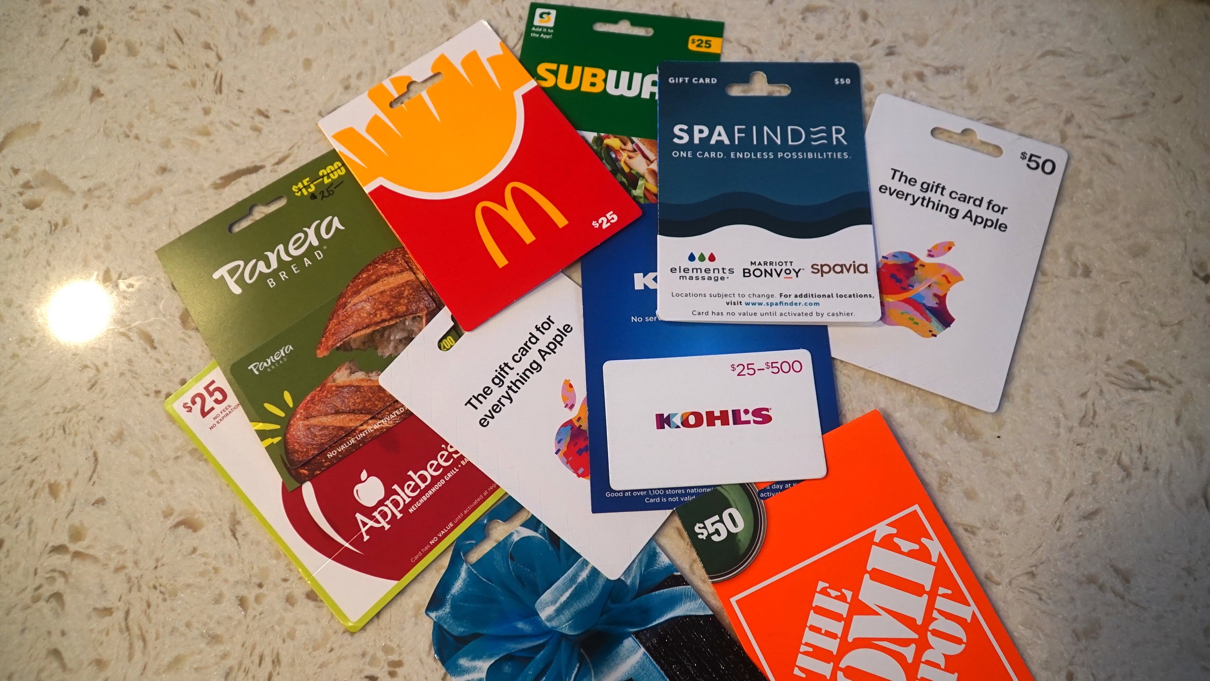 A variety of gift cards scattered on a surface, including McDonald's, Subway, Spafinder, and more, displaying different monetary values