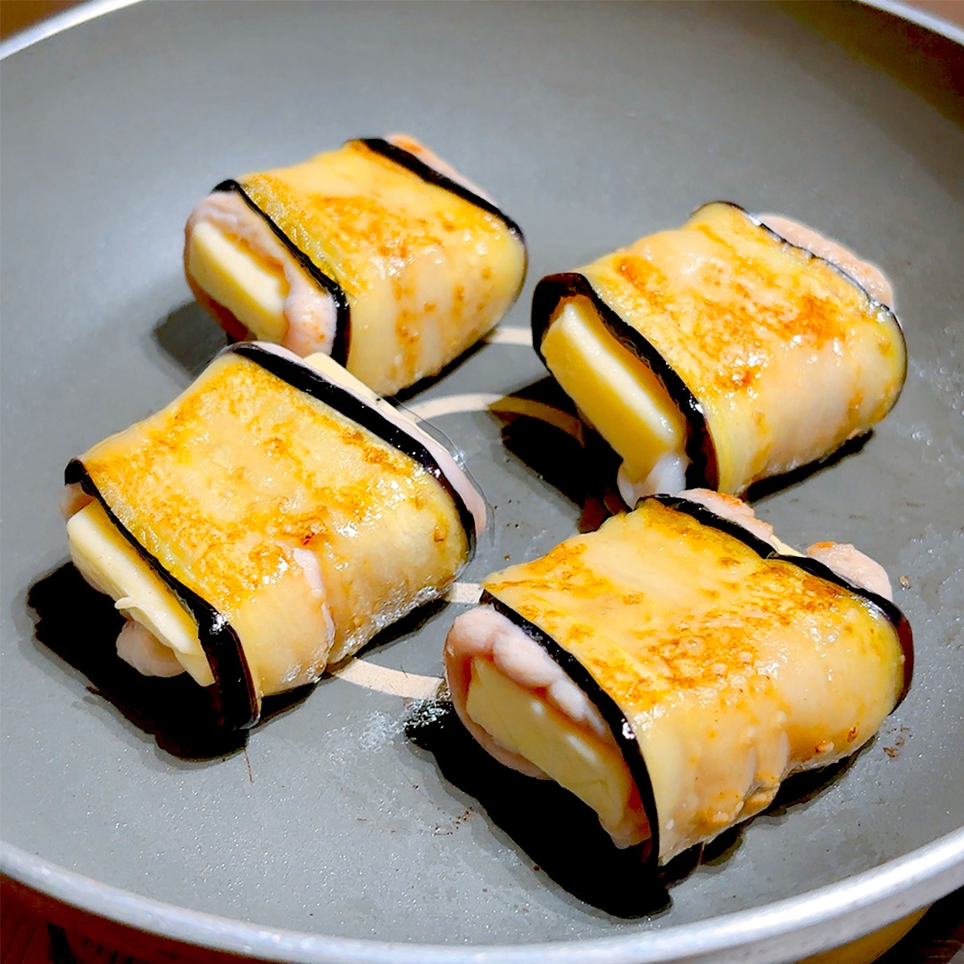 フライパンで焼かれているスクエア形のチーズと海苔で巻かれた料理。