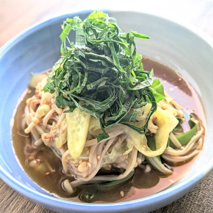 冷たい料理が器に盛られ、上に刻んだ大葉と野菜がのせられています。スープが器に注がれています。