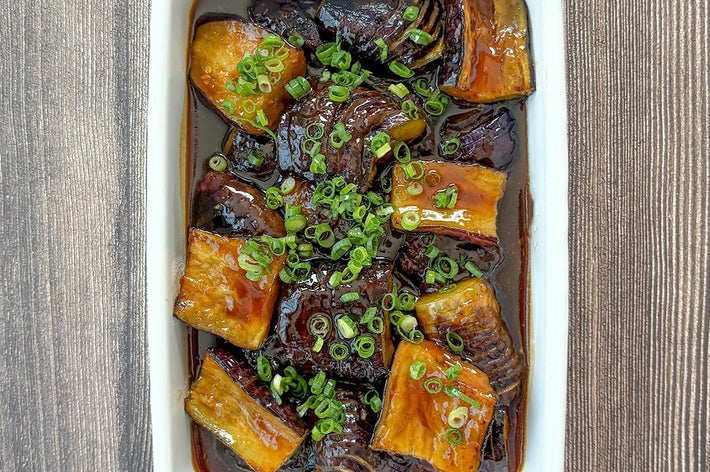 ホーローに盛られたなすの甘辛炒め。小ネギが飾られている。