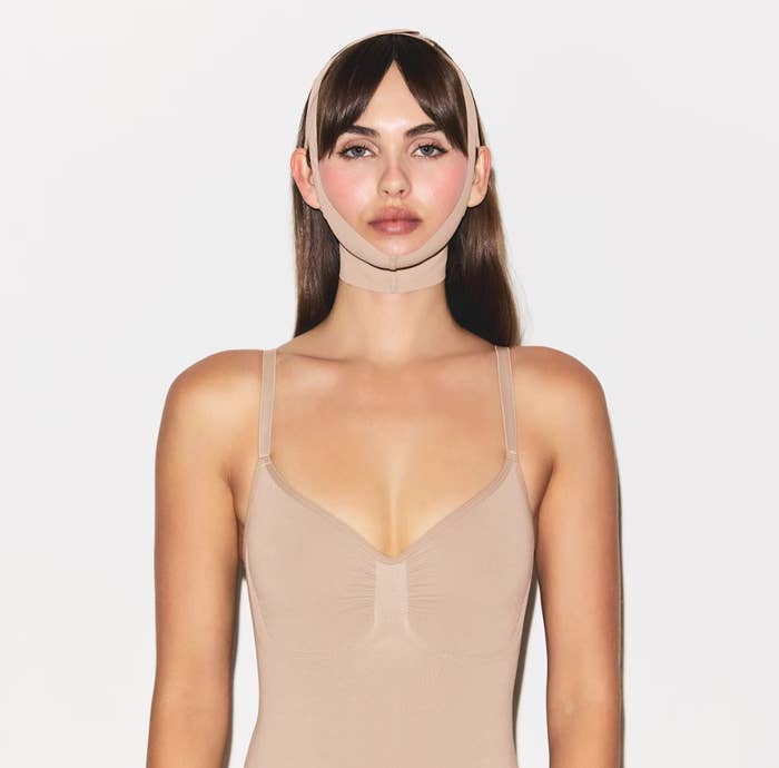 Skims model wearing a fitted face wrap and a sleeveless top