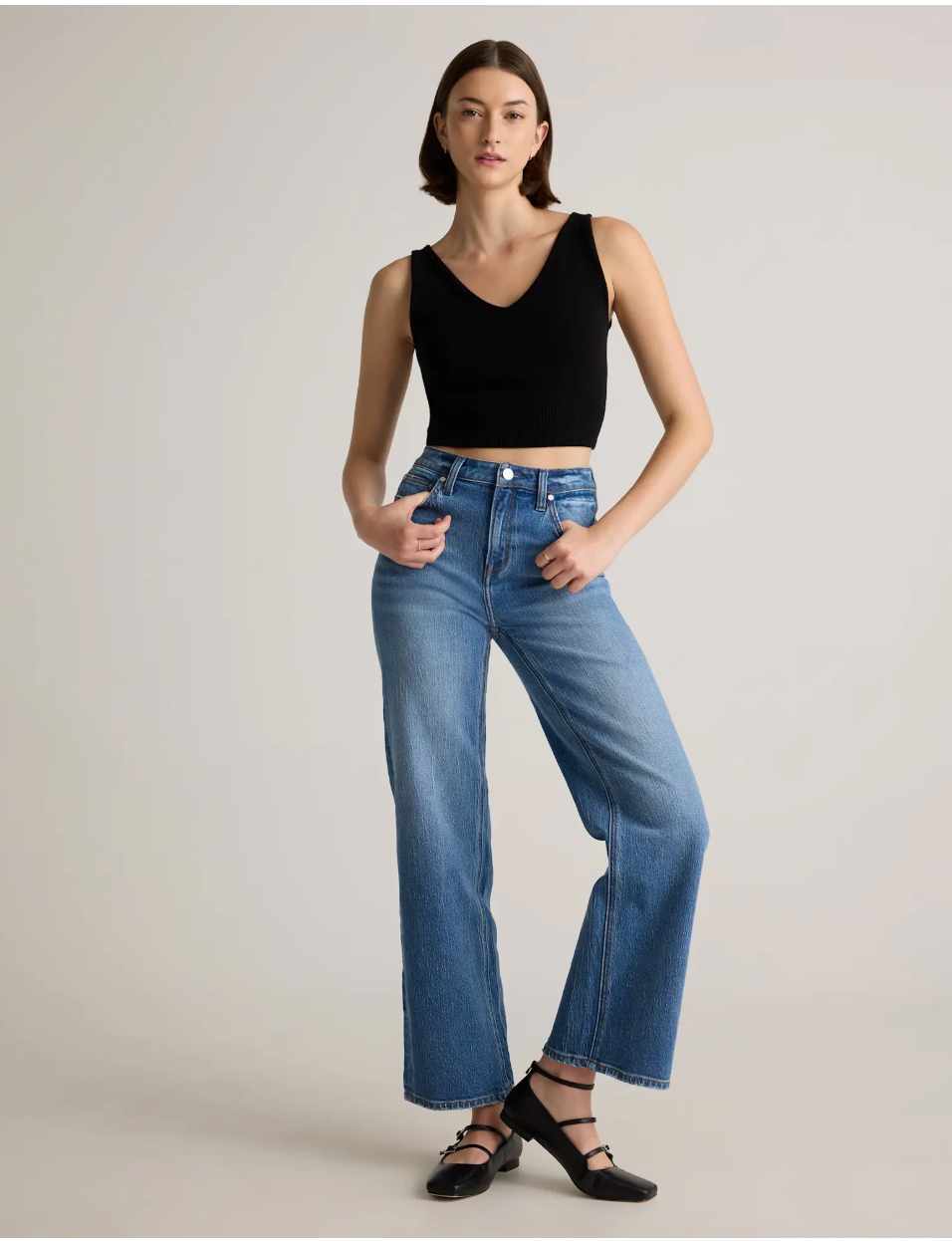 Model wears a sleeveless achromatic  apical  and bluish  jeans with achromatic  shoes, successful  a neutral airs  for a buying  article