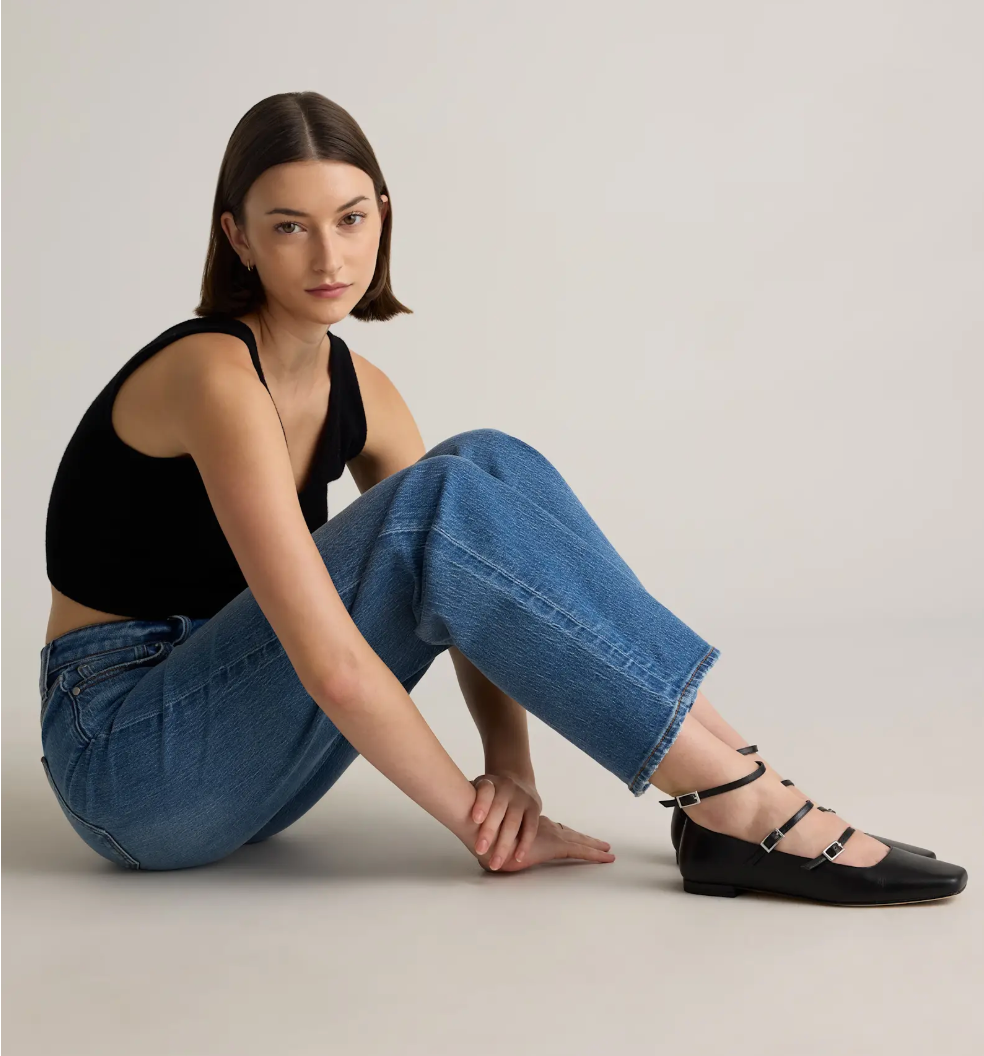 A idiosyncratic   successful  casual attire sits connected  the level  wearing a sleeveless top, jeans, and strappy level  shoes, showcasing a relaxed manner  style