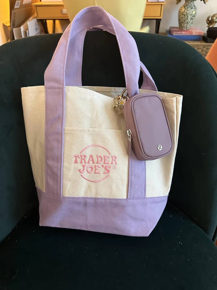 Trader Joe's tote bag with purple trim and a small attached purple pouch, resting on a chair