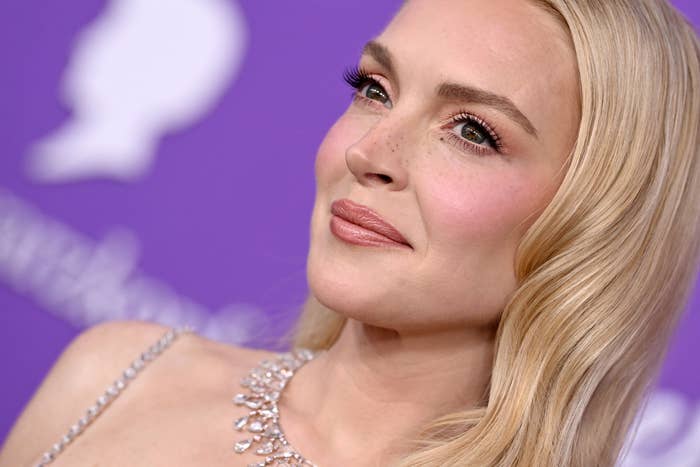 Lindsay Lohan on red carpet in an elegant dress with gem details, looking off-camera with a serene expression