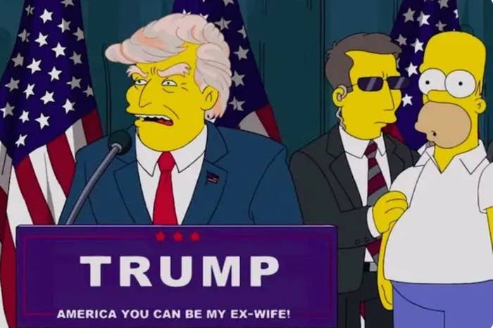 Animated character resembling a politician at a podium labeled &quot;TRUMP,&quot; with bodyguard and another character nearby, in a setting with flags