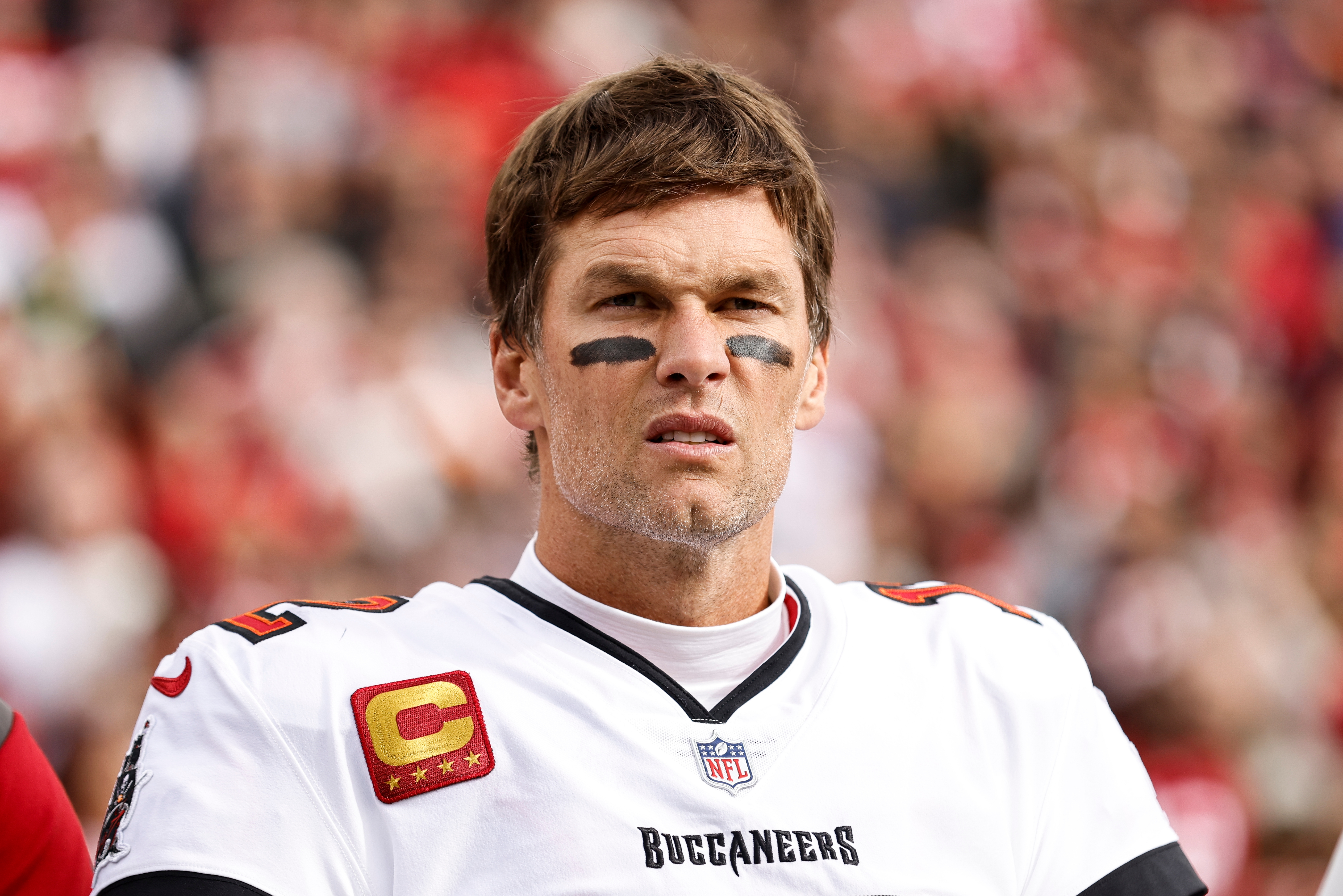 A football player wearing a uniform with captain insignia, looking focused during a game