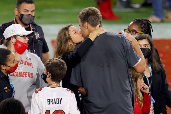 A person in a sports jersey is surrounded by family and fans, being embraced by someone amid a crowd, likely post-event celebration