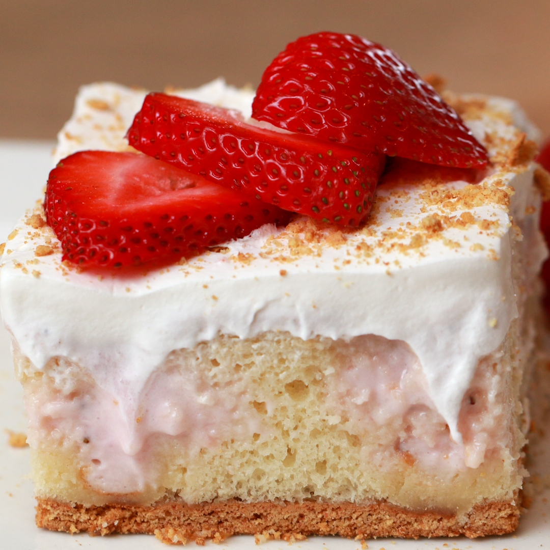 Slice of cake with cream frosting, topped with fresh strawberry slices