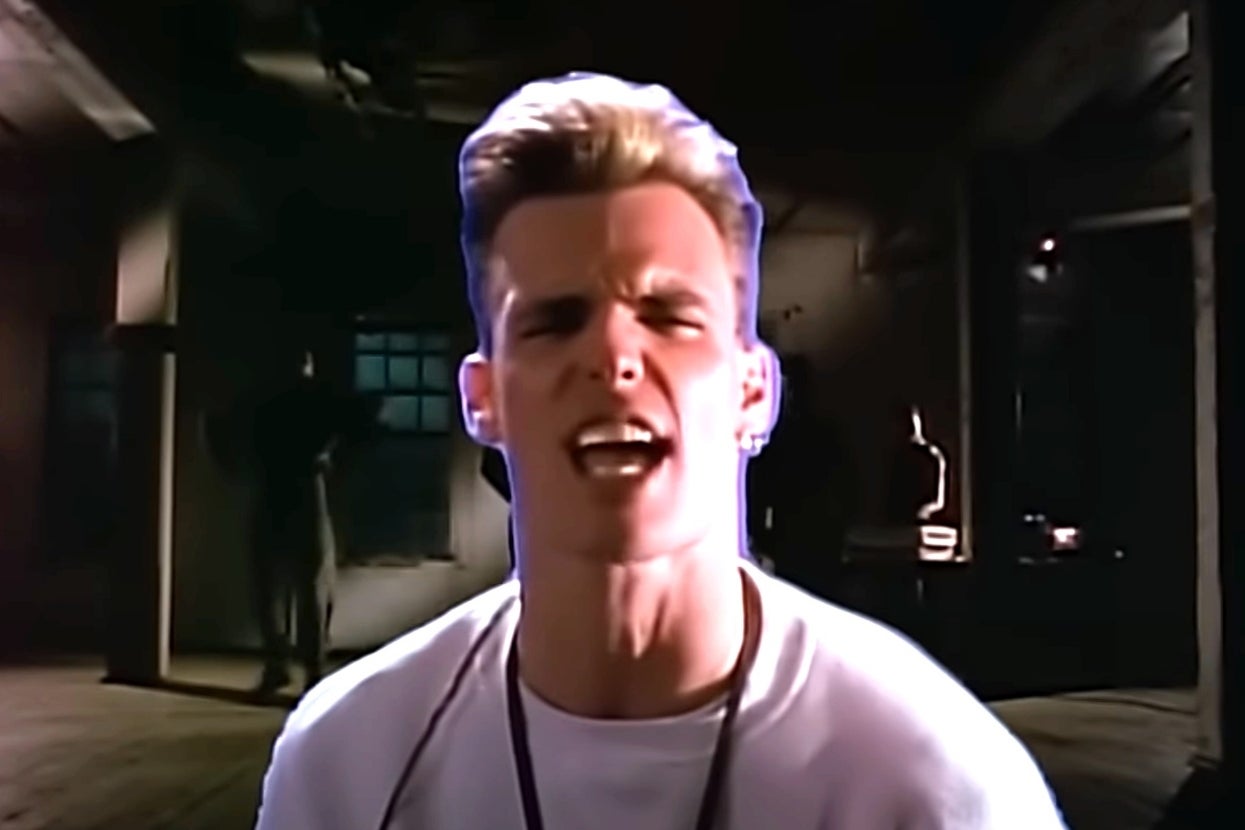 Vanilla Ice performing in a dimly lit room, wearing a t-shirt and necklace