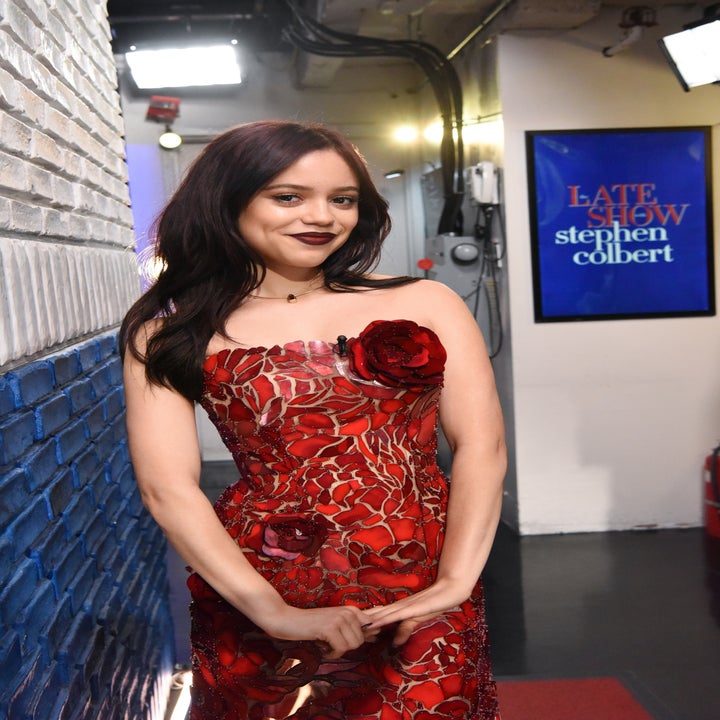 Person in a floral-patterned dress poses near a "Late Show with Stephen Colbert" sign