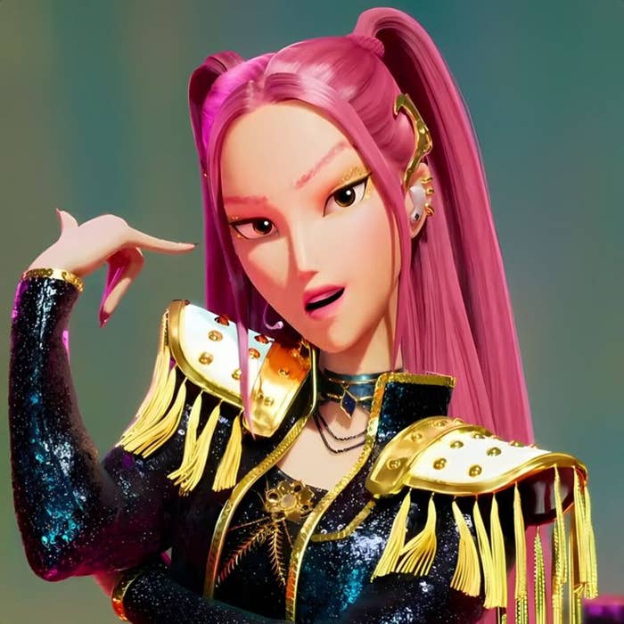 Personaje animado con cabello rosado, vistiendo una chaqueta con hombreras doradas y flecos, en pose expresiva