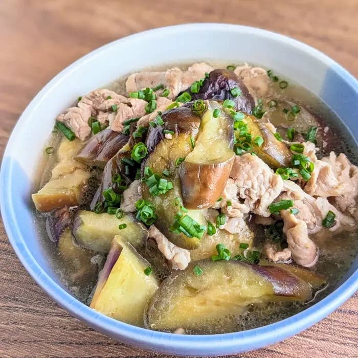 なすと豚こま切れ肉の白だし煮浸しが器に盛られている。刻んだ小ネギがトッピングされている。