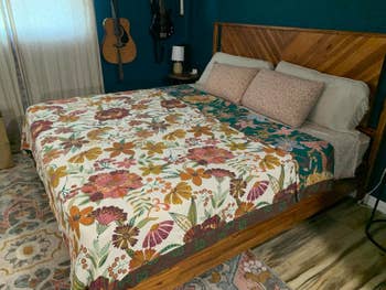 Cozy chamber with a woody furniture featuring a floral quilt, 2 decorative pillows, and guitars hanging connected the wall