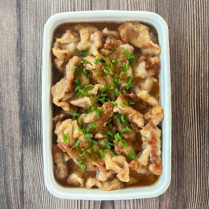 豚こま切れ肉の梅だれ和えがホーローに入っている。小ネギが散らされている。