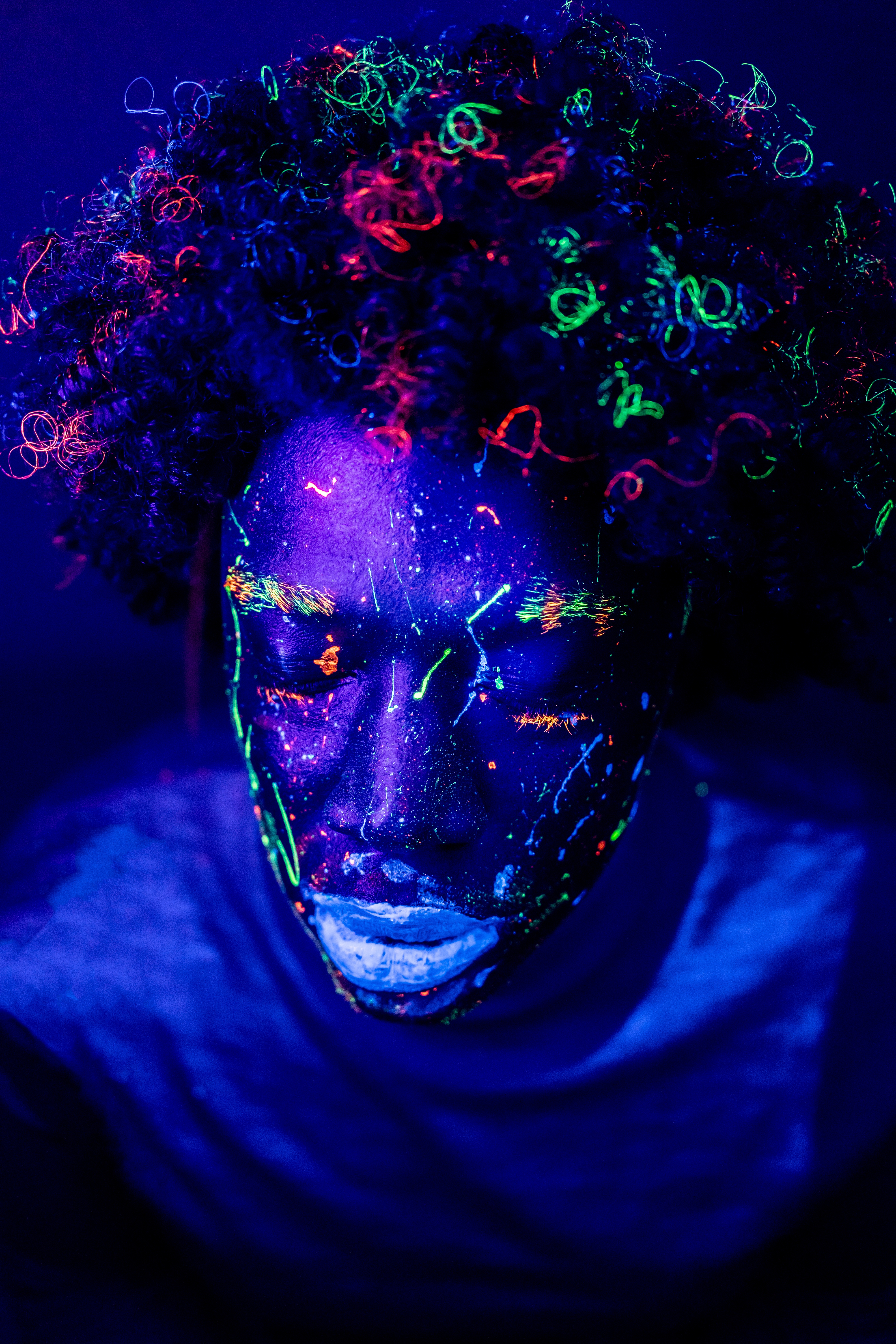 Person with colorful neon face paint under blacklight