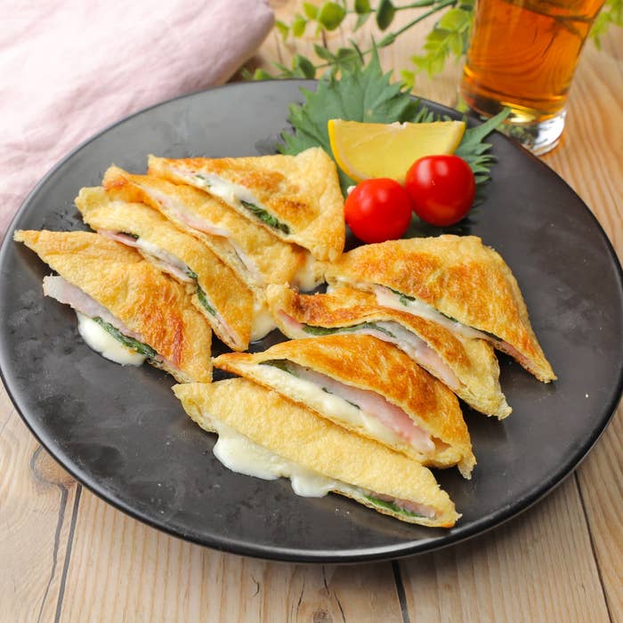 お皿に盛られた油揚げサンド、チーズ入り。添えられたミニトマトとレモン。