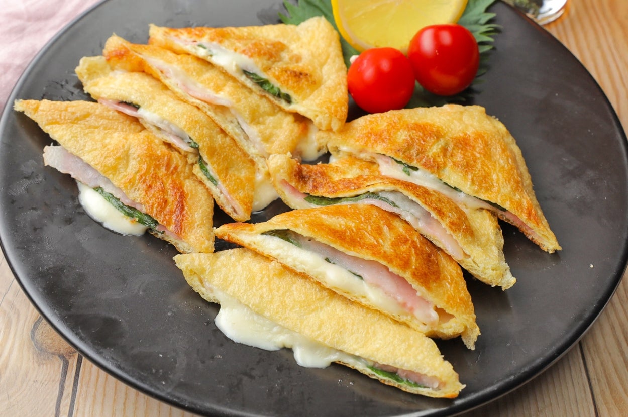 皿に盛られたホットサンドイッチ、トマト、レモン添え。飲み物が隣にある。