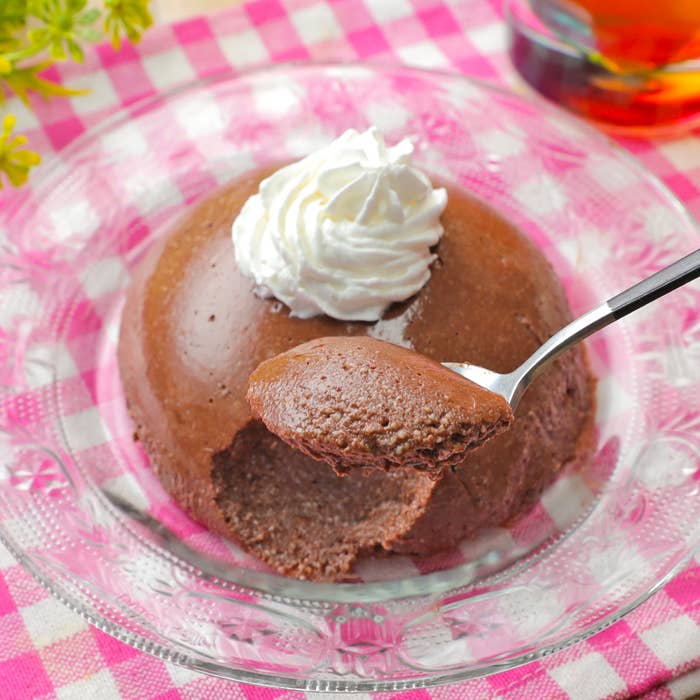 チョコムースに生クリームがトッピングされ、スプーンですくわれています。チェック柄のテーブルクロスの上に置かれています。