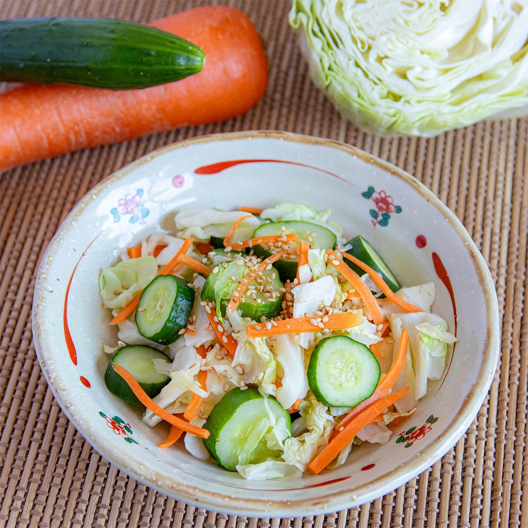 お皿に盛られたキャベツ、きゅうり、にんじんの浅漬け。ボウルの外に野菜が置かれている。