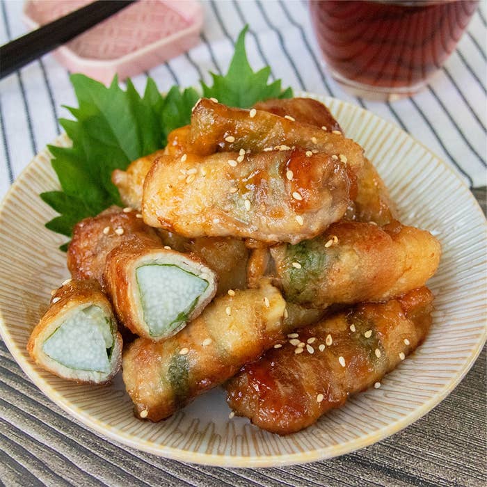 白い皿に盛られた長芋と大葉の肉巻き、白いりごまが散らしてある。