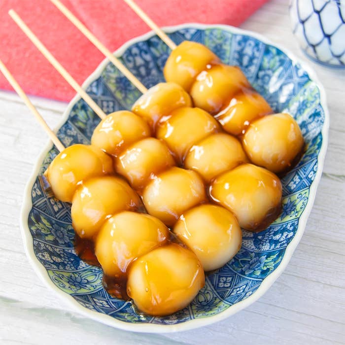 皿に並んだ白玉粉で作ったみたらし団子の串。甘辛だれがかかっている。