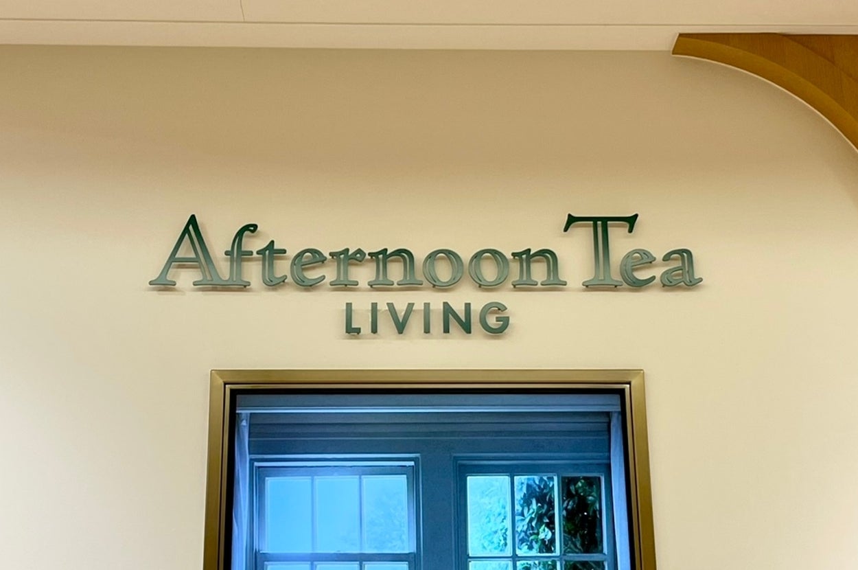 店内に「Afternoon Tea LIVING」と書かれた看板。窓際にティーセットが並べられたテーブルの写真がある。