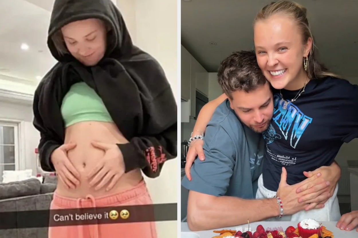 Two people hugging in a kitchen, smiling joyfully over a cake with berries. Both are in casual outfits, expressing happiness and closeness