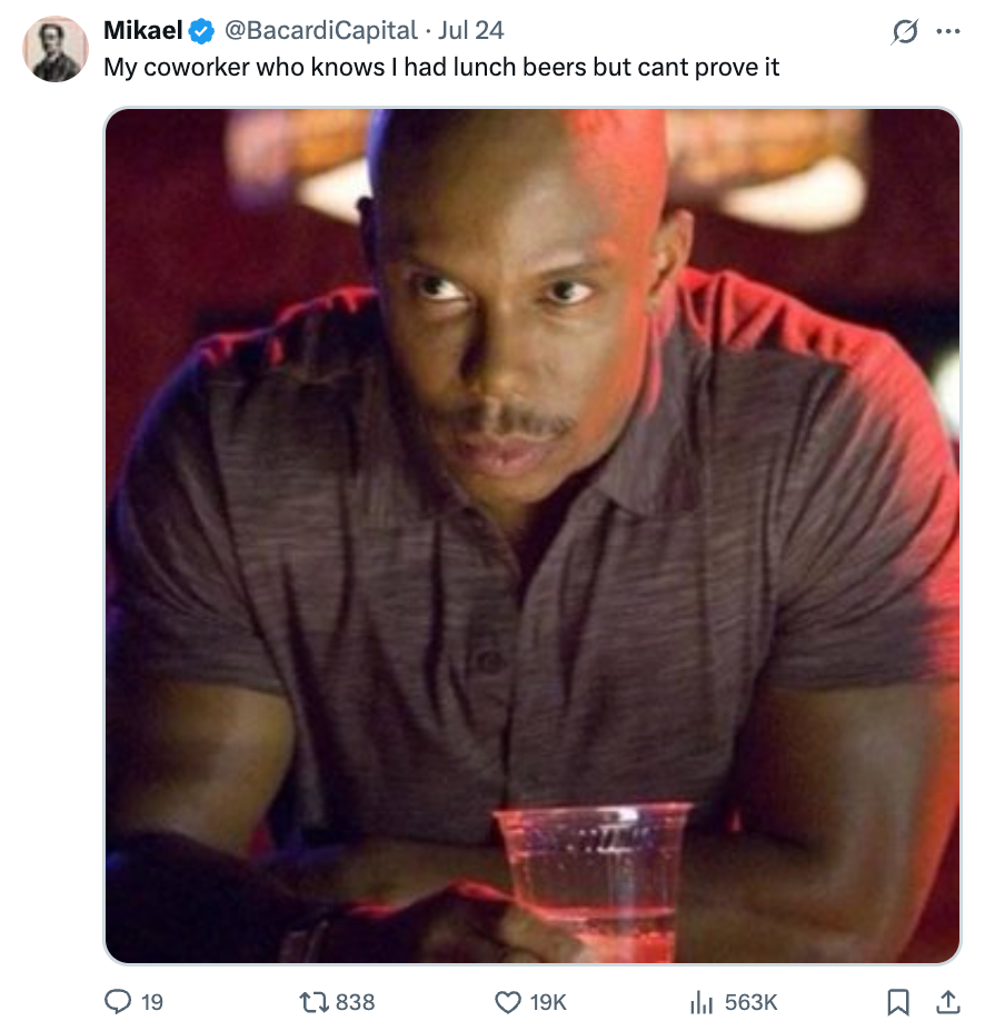 Doakes with a serious expression sits with a drink, beneath a humorous tweet about someone suspecting they had beers at lunch