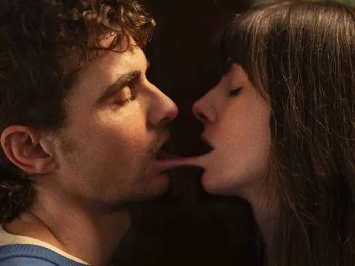 Dos personas con rostros cercanos, una extiende la lengua hacia la otra, creando una escena curiosa e inusual