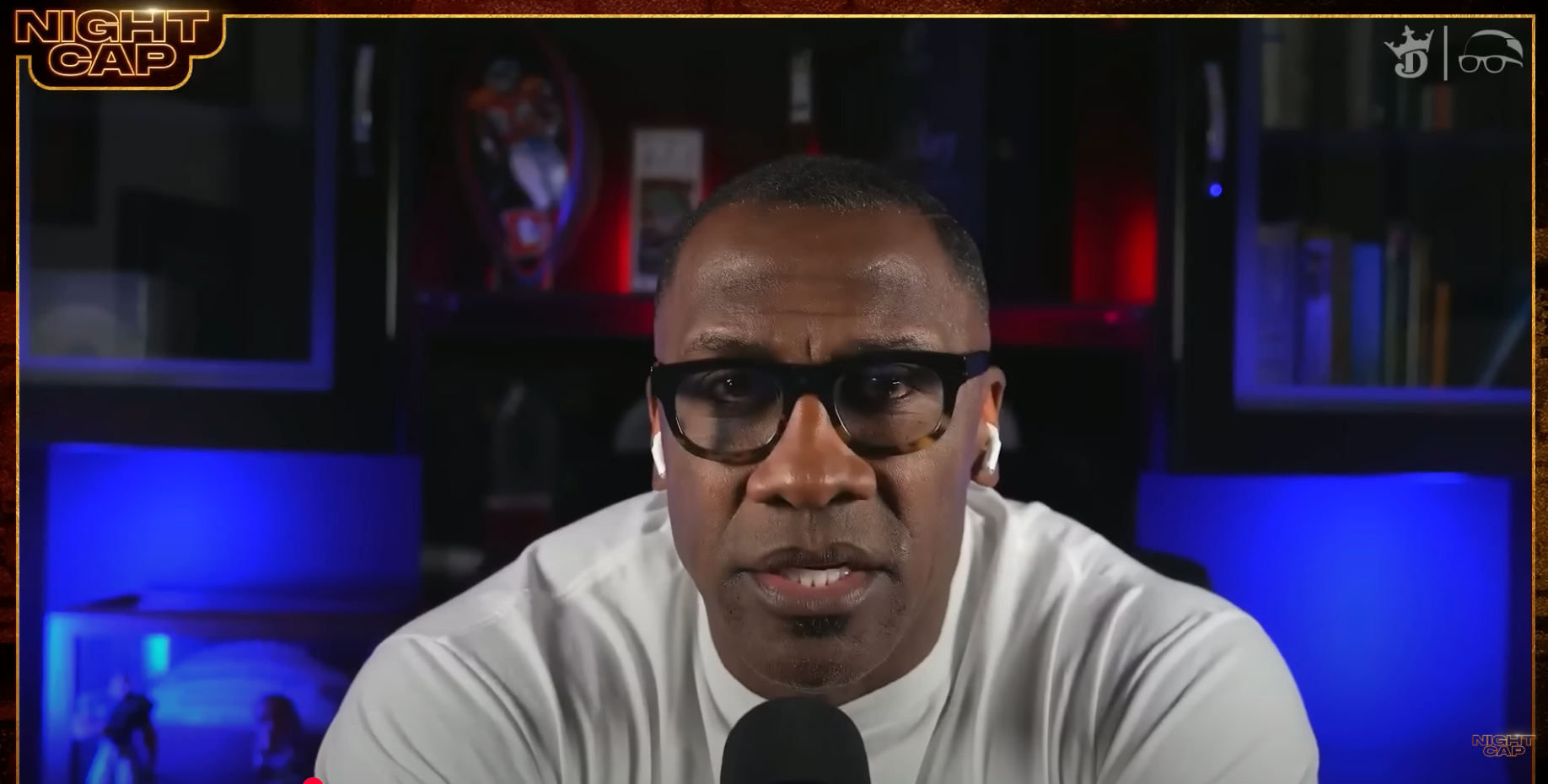 Person wearing glasses with earphones is speaking, set against bookshelves with ambient lighting. The text says &quot;Night Cap&quot; in the corner