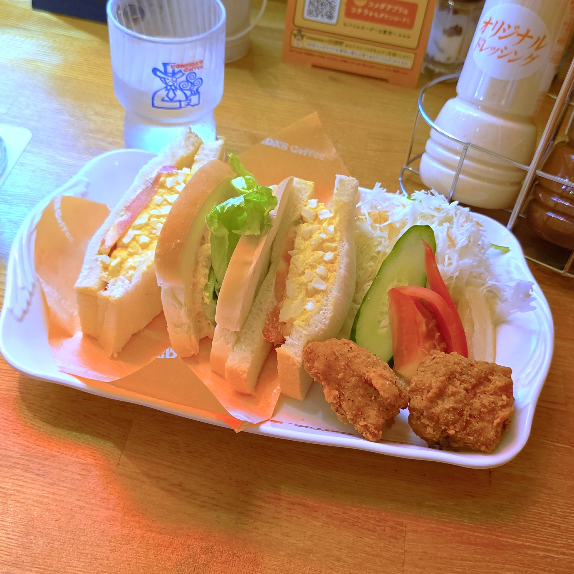 サンドイッチ、野菜、フライドチキンが盛り付けられたプレート。添えられたキャベツとトマトが彩りを添えている。