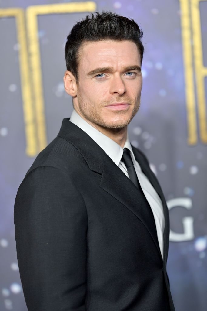 Man in a tailored suit at a celebrity event, posing with a neutral expression