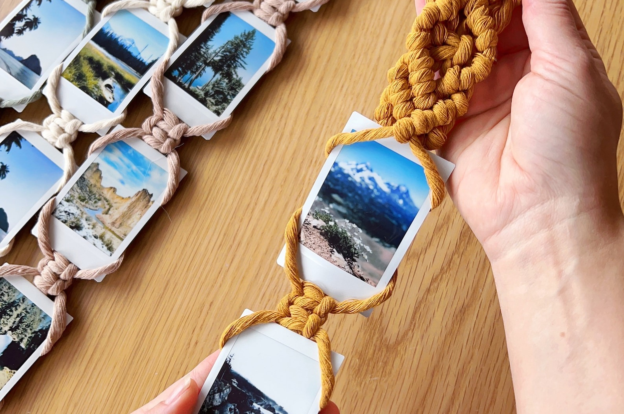 Hand holding macramé photo display with polaroid pictures, showcasing a stylish, bohemian way to organize and decorate with personal photos
