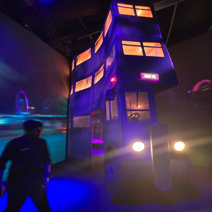 Autobús de dos pisos con diseño inclinado y ventanas iluminadas, parte de una exhibición. Persona caminando cerca