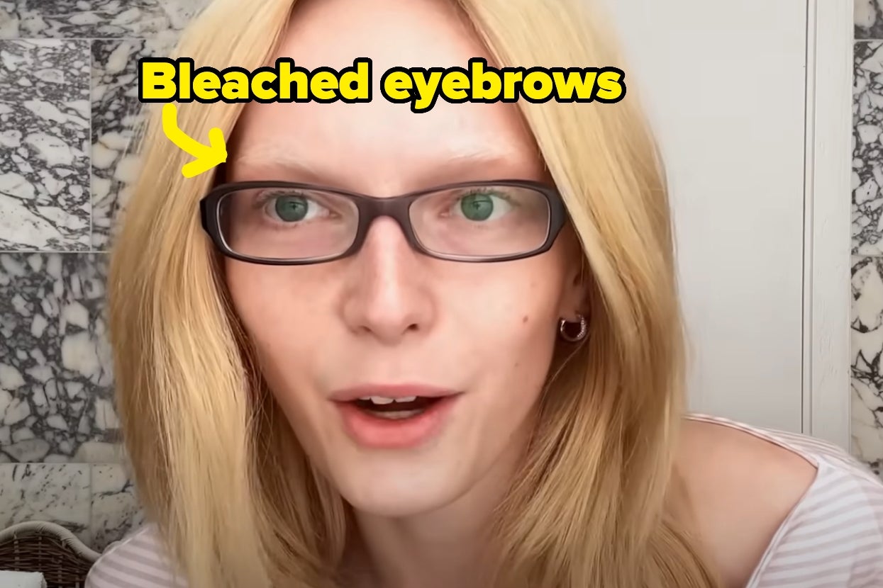 Person with glasses and bleached eyebrows sits indoors, wearing a white top and small earrings. Text overlay highlights "Bleached eyebrows."