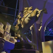 Escultura de un caballo encabritado con un jinete, ubicada en un interior con arcos y luz ambiental