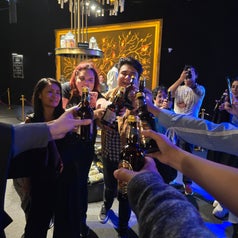 Personas brindando con botellas en un evento social, sonriendo y celebrando en un ambiente interior