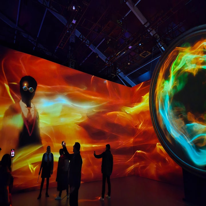Exposición de arte digital interactiva con personas observando proyecciones visuales en una sala oscura