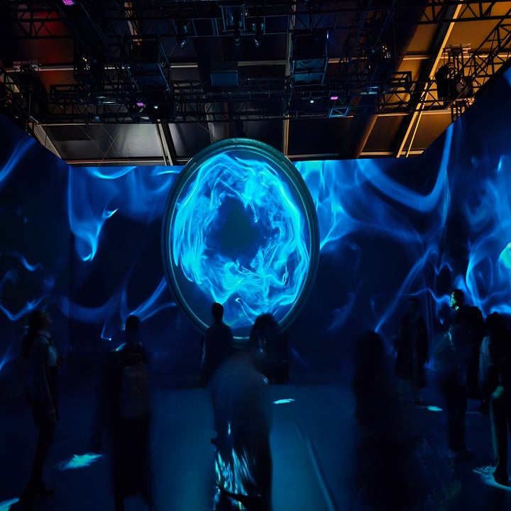 Personas observan una proyección de arte digital con un diseño circular abstracto en un espacio oscuro y futurista