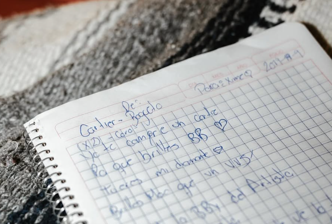 Cuaderno abierto con una página de notas escritas a mano, con referencia a canciones o letras