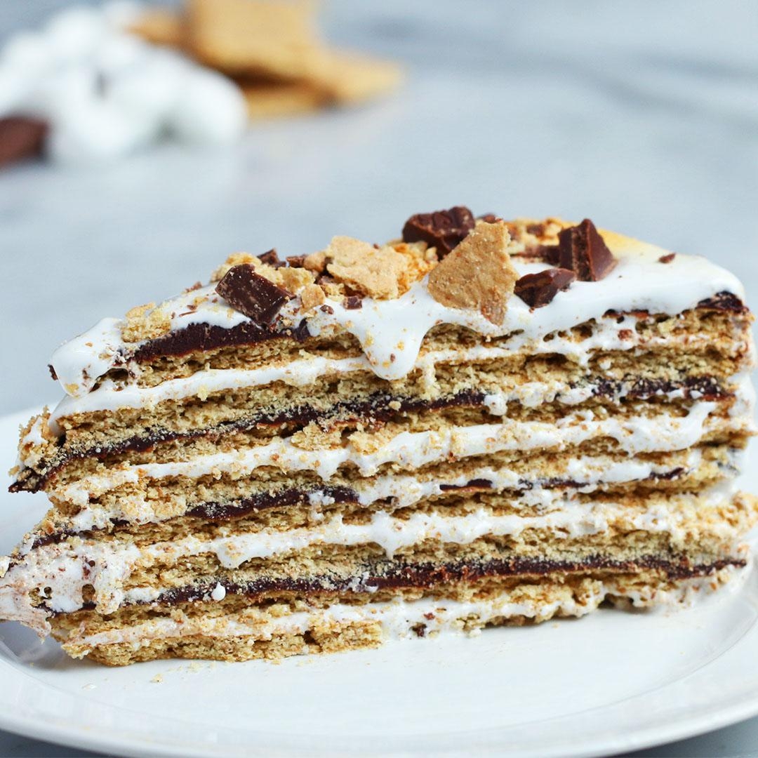 Layered dessert with graham crackers, chocolate, and marshmallow cream on a plate, resembling a s'mores cake