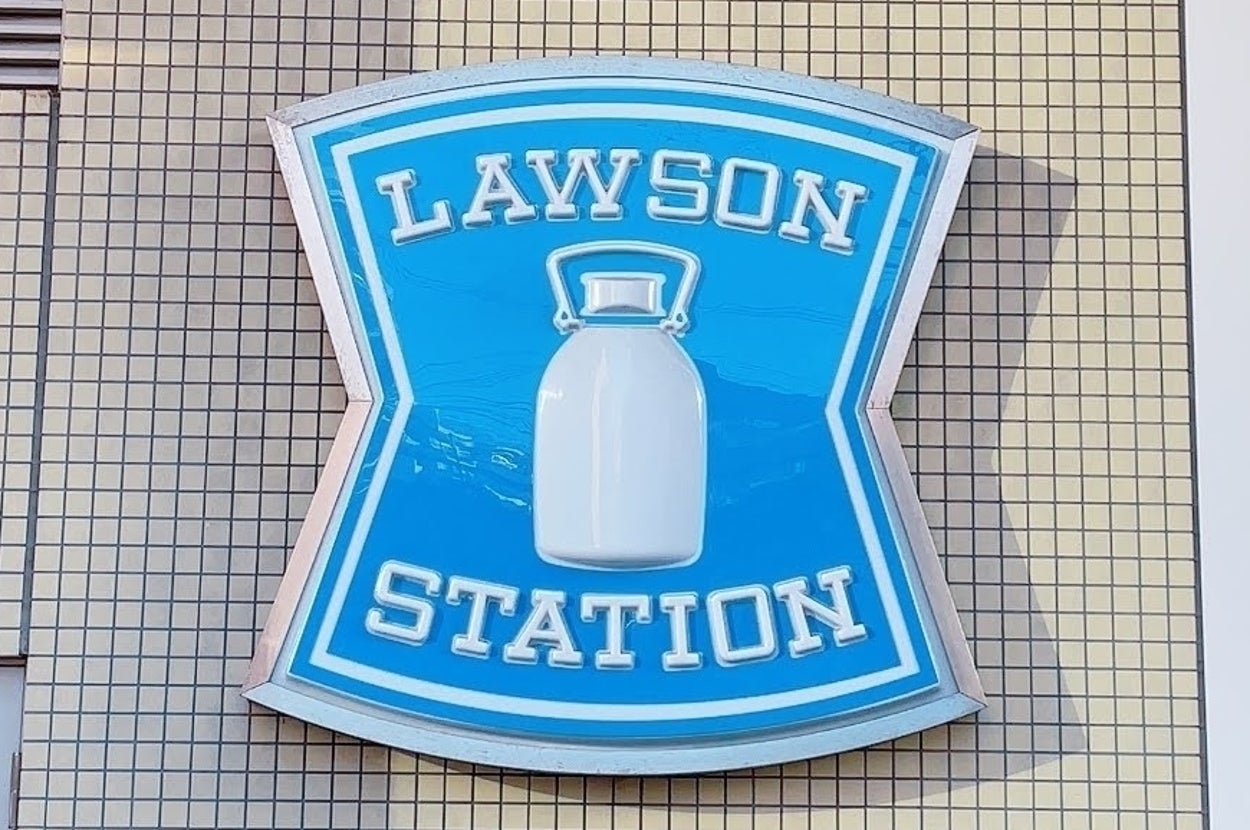 ロゴ壁看板に「LAWSON STATION」と書かれ、中央にミルク缶のイラストが描かれています。