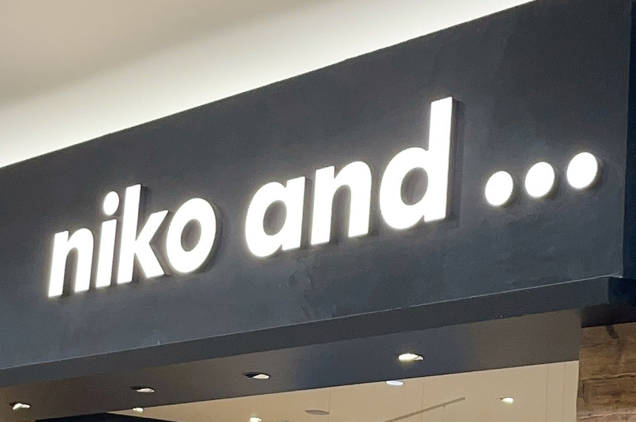 Storefront of "niko and ..." featuring various clothing and items on display, including casual outfits and home goods