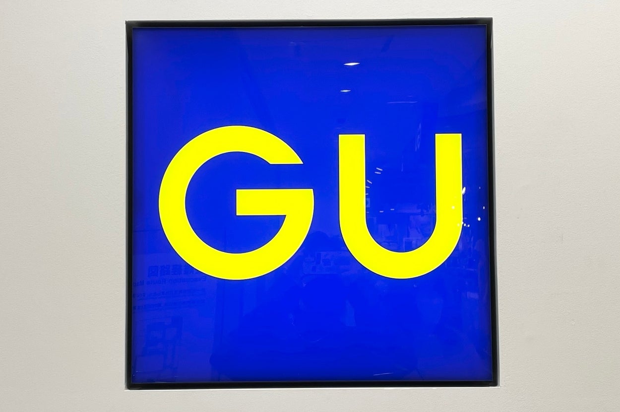 A square sign displays the letters "GU" in bold font