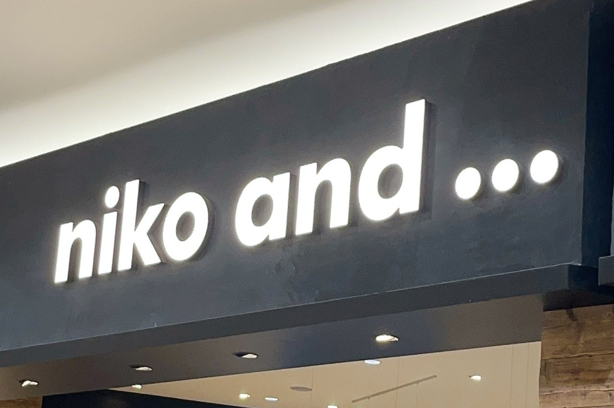 Clothing and lifestyle store with wooden accents, displaying various garments and items under the sign "niko and ..."