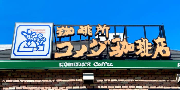 コメダ珈琲店の看板が写っています。青空の下に位置しています。