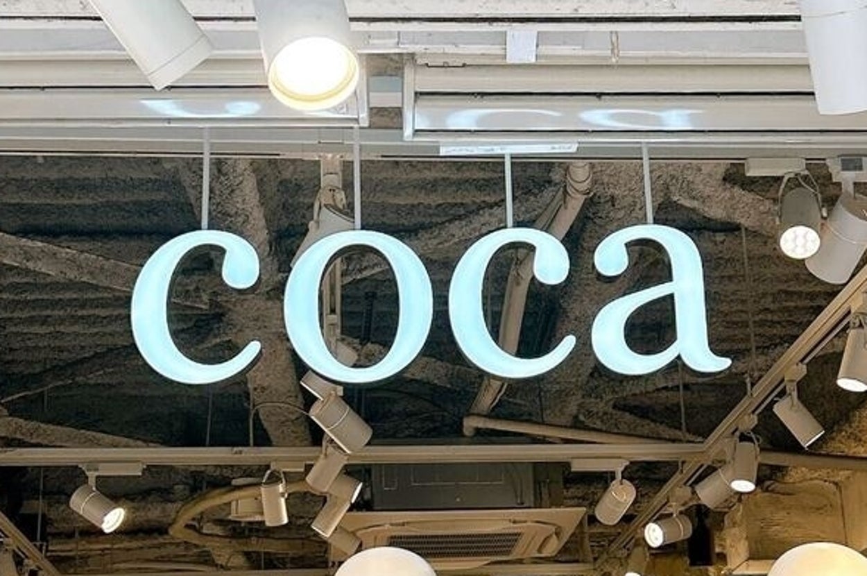 店内に「coca」と表示されたサイン。天井には多くのライトが設置されています。